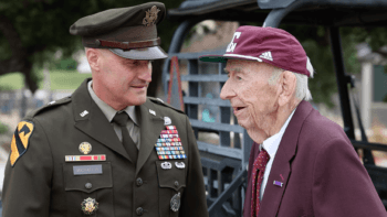 an image of an older man in maroon speaking with a younger man in a U.S. army uniform